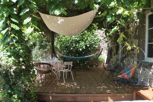 a patio with a table and chairs and a hammock at L'Ancienne Ecole in Vernassal