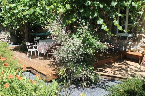 a garden with a table and chairs on a wooden deck at L'Ancienne Ecole in Vernassal