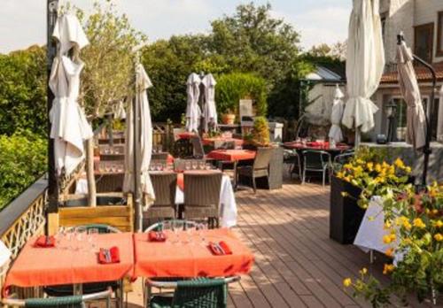 a patio with tables and chairs and umbrellas at Auberge de la garenne in Saint-Rémy-lʼHonoré