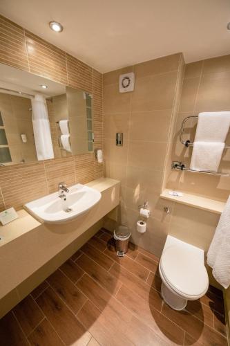 a bathroom with a sink and a toilet and a mirror at Holiday Inn Newport by IHG in Newport