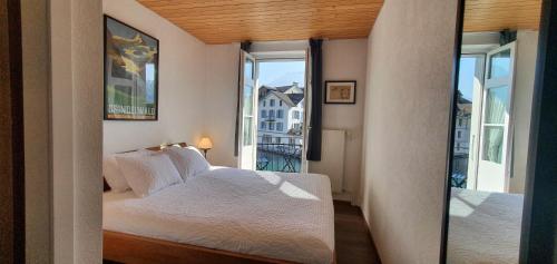 a bedroom with a bed and a large window at The Aarburg Hotel & Café in Interlaken