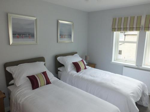 two beds in a room with white walls at Luxury Riverbank Apartment, Nairn in Nairn