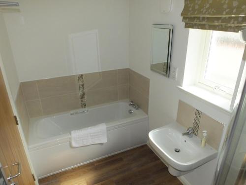 a white bathroom with a tub and a sink at Luxury Riverbank Apartment, Nairn in Nairn