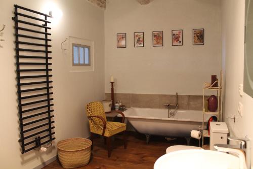 a bathroom with a tub and a table and a chair at L'Ancienne Ecole in Vernassal