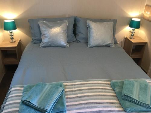 a bed with two pillows and towels on it at Poppy Lodge in Boat of Garten