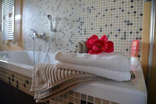 a bathroom with towels and a red flower on a sink at Le Ali del Falco in Cuceglio