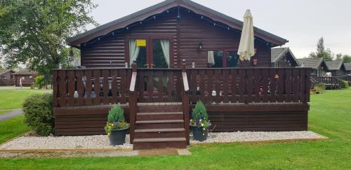 a small cabin with a wooden fence and stairs at Cotswold Lodges in Cirencester