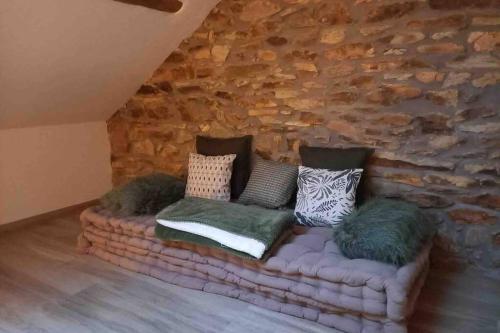 a couch in a room with a stone wall at Le grenier de Charlotte in Libin