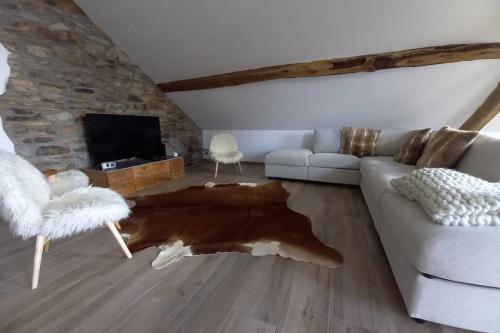 a living room with a couch and a tv at Le grenier de Charlotte in Libin