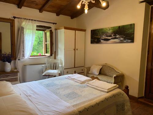 a bedroom with a bed and a chair and a window at Relax totale nel Bosco Lucca in Ghivizzano