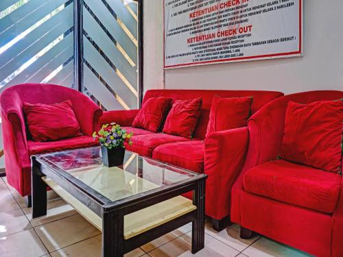 a living room with two red couches and a coffee table at Penginapan Marsya Prima Syariah in Jakarta