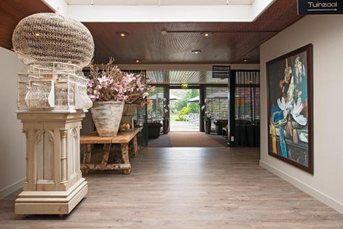a hallway with a table and vases of flowers at Fletcher Hotel Restaurant Prinsen in Vlijmen