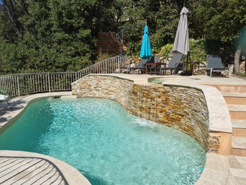 uma piscina com uma parede de tijolos à volta em Appart "Pins & parasol", piscine chauffée et bain à remous em Taradeau