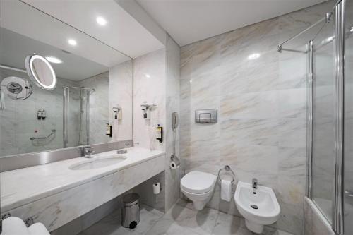 a bathroom with a sink and a toilet and a shower at Hotel Marina Atlântico in Ponta Delgada