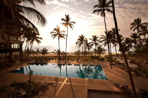 a view of the pool at the resort with palm trees at Novotel Mumbai Juhu Beach in Mumbai