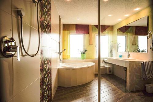 a bathroom with a tub and a sink at Hotel Restaurant Wolfsschlucht GmbH in Bad Münstereifel