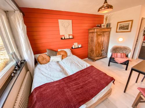 um quarto com uma parede vermelha com uma cama e uma cadeira em Studio MIA - Cosy & Comfortable - Glacier Paradise em Zermatt