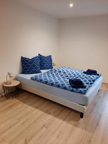 a bedroom with a bed with blue pillows and a table at Mill D'Arx in Château