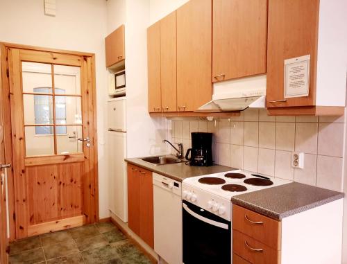Il comprend une petite cuisine équipée d'une cuisinière et d'un évier. dans l'établissement Lapin Kutsu Luulampi Apartments, à Saariselka