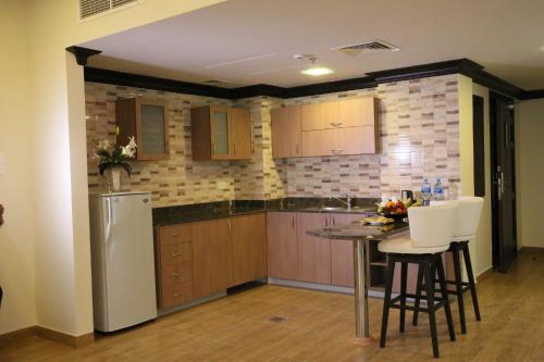 a kitchen with a table and white chairs at Royal Phoenicia Hotel in Manama