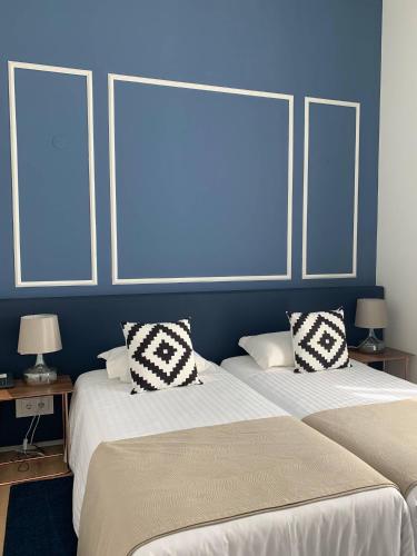 two beds in a room with blue walls at Hotel Farol in Praia da Barra