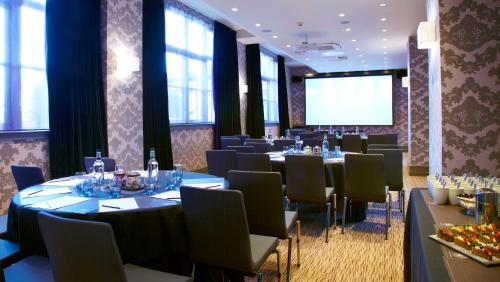 a conference room with tables and chairs and a screen at Malmaison Newcastle in Newcastle upon Tyne
