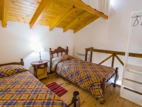 Un dormitorio con dos camas y suelo de madera. en Departamentos De la Plaza, en Villa La Angostura