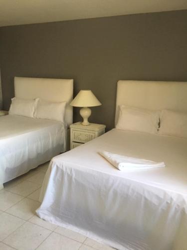 a bedroom with two beds and a table with a lamp at Hotel Maracas Punta Cana in Punta Cana