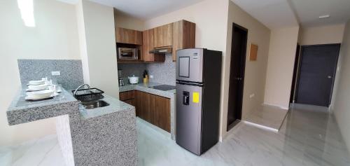 a kitchen with a stainless steel refrigerator and wooden cabinets at NCG SUITE Centro in Guayaquil