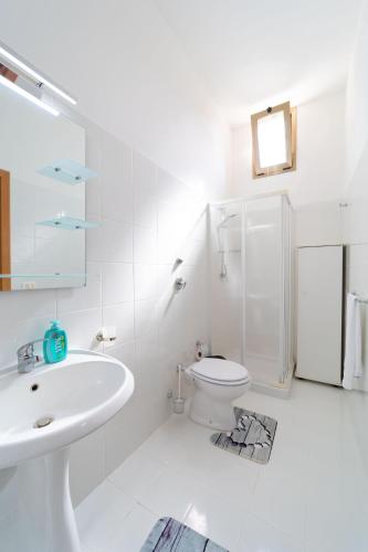 a white bathroom with a sink and a toilet at VaVillaVà Appartamenti in Centro in Marsala