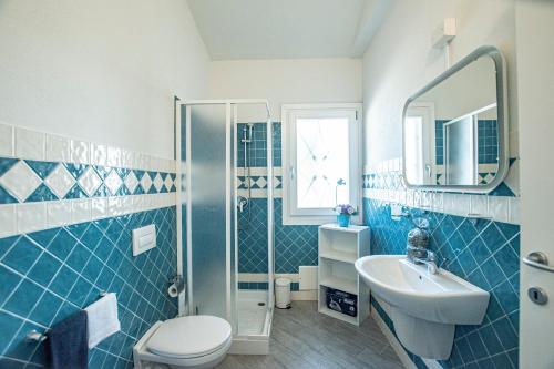 bagno piastrellato blu con lavandino e servizi igienici di Villa Girasole a Valledoria