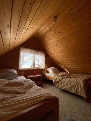 a room with two beds in a wooden cabin at Avoti in Jūrkalne