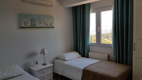 a bedroom with two beds and a window at Rosalalinda - cosy semi-detached home with sea views and large terrace in Moraira