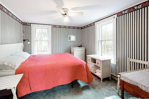 1 Schlafzimmer mit einem roten Bett und 2 Fenstern in der Unterkunft The Rose Cottage in Nantucket
