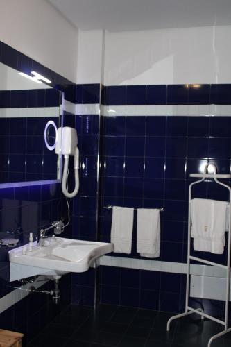 a blue tiled bathroom with a sink and towels at Artemisia Palace Hotel in Palermo