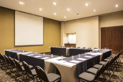 a set of tables and chairs in a room with a screen at Fiesta Inn Chihuahua Fashion Mall in Chihuahua