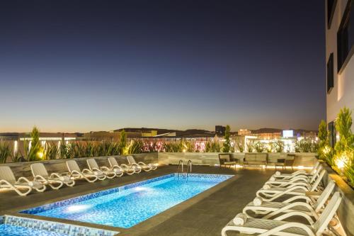 una piscina de hotel con tumbonas y una piscina en Fiesta Inn Chihuahua Fashion Mall en Chihuahua