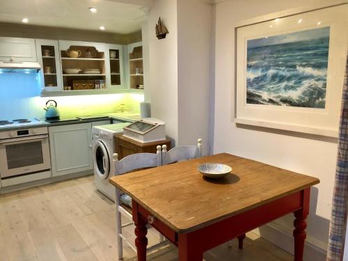 a kitchen with a wooden table and a dining room at Sixpence Cottage in Penryn