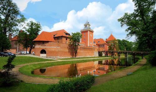 a building with a clock tower next to a river at Hotel Krasicki in Lidzbark Warmiński
