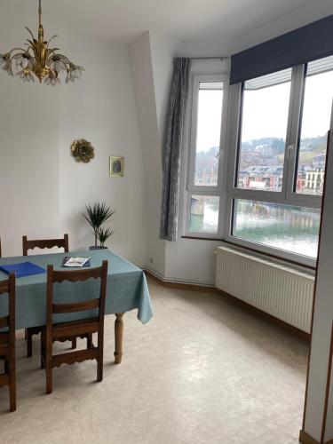 a dining room with a table and two windows at le coeur de ville in Dinant