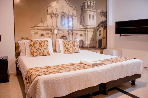 um quarto com uma cama grande e uma pintura na parede em HOTEL TORRE REAL em Popayan