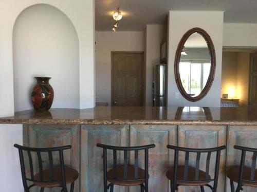 a kitchen with a counter with chairs and a mirror at Ocean View Cabo Condo Create Memories!! in San José del Cabo