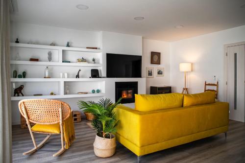 sala de estar con sofá amarillo y silla en Casa dos Rosas, en Gavião