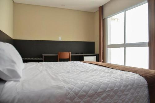 a bedroom with a large white bed with a window at M Tower Hotel in Pelotas