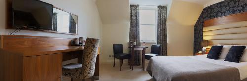 a hotel room with a bed and a desk and a television at Westport Country Lodge Hotel in Westport