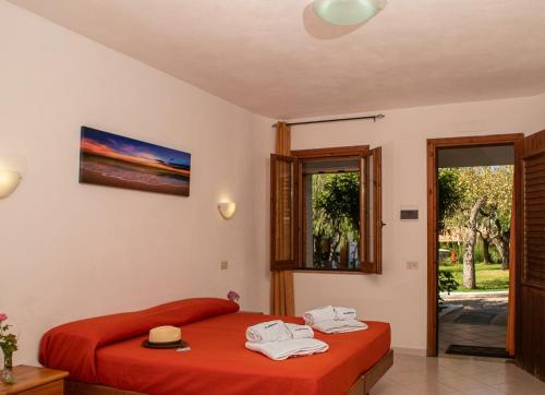 una camera da letto con un letto con lenzuola rosse e asciugamani di Villaggio La Pizzuta a Parghelia