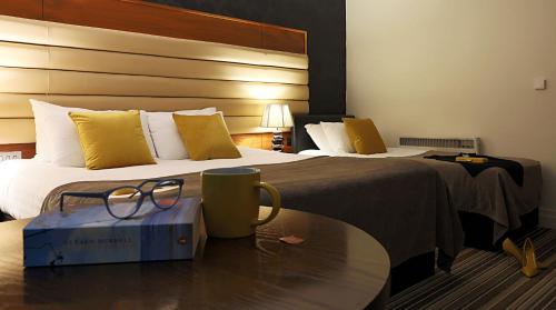 a hotel room with a bed and a table with glasses on it at Westport Country Lodge Hotel in Westport