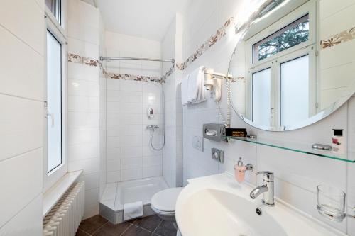 a bathroom with a sink and a toilet and a mirror at Hotel Federale in Lugano