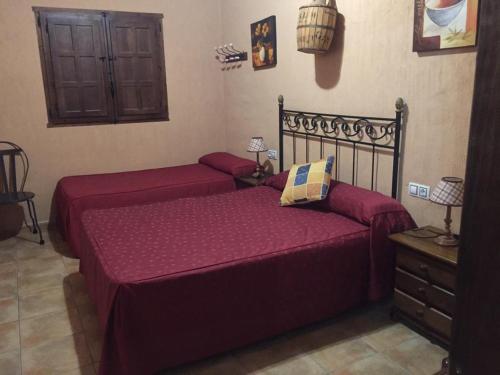2 camas en un dormitorio con sábanas rojas en Casas Rurales Hoz del Júcar, en Alcalá del Júcar