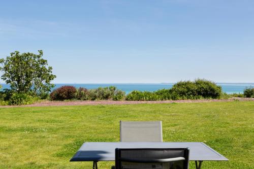 a table and a chair sitting in a field at La Metairie-du-Vauhariot - Vue Mer et Mont Saint Michel - Piscine Chauffée - Accès GR34 in Cancale